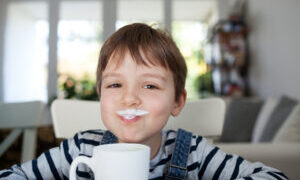 Adorable boy drinking milk or yogurt, shallow depth of field
