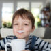 Adorable boy drinking milk or yogurt, shallow depth of field